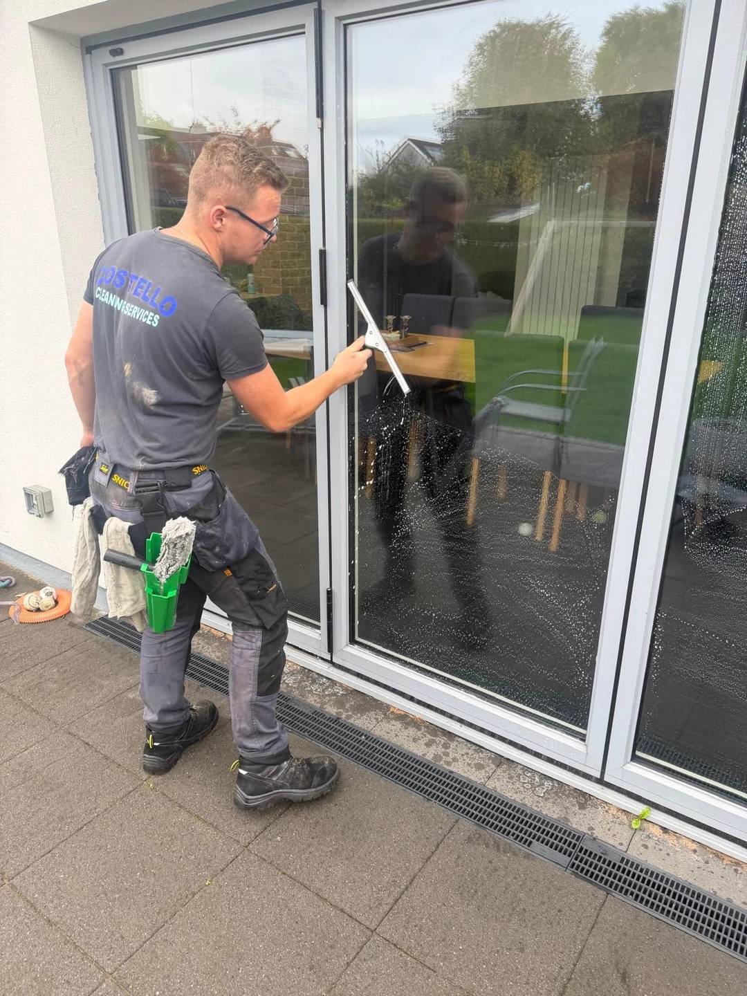 Adam Costello cleaning glass doors with a squeegee